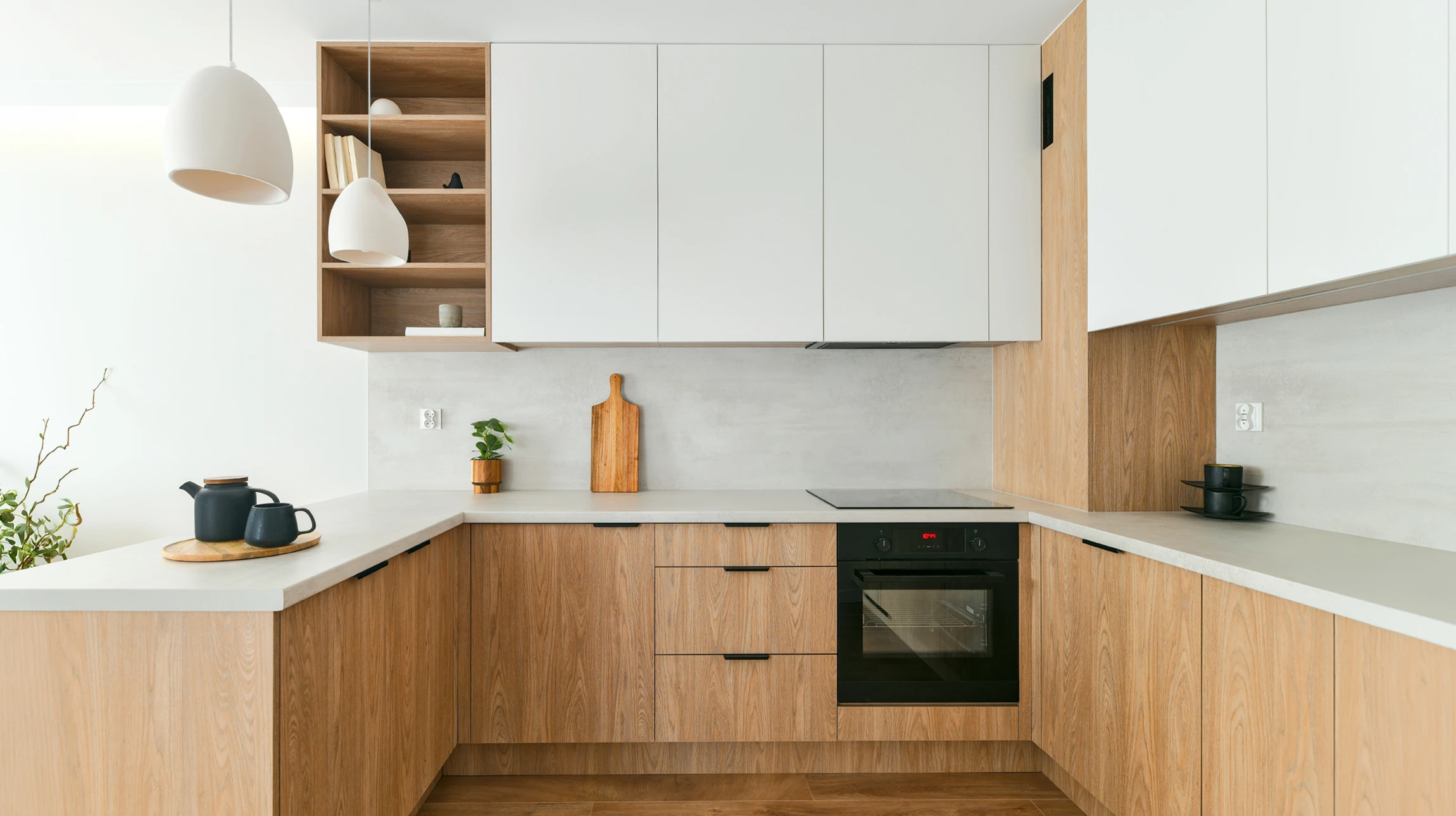 Cuisine moderne blanche avec plan de travail en bois clair, électroménager intégré et accessoires de cuisson disposés
