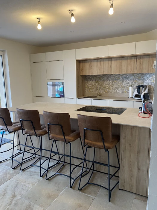 Un artisan menuisier travaille dans un atelier intérieur, assemblant une structure triangulaire en bois massif sur sol béton