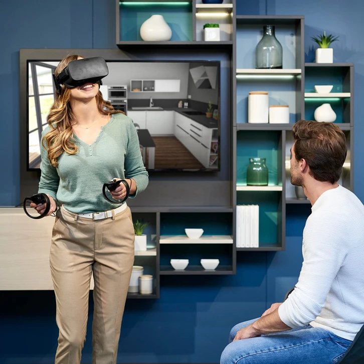 Couple souriant utilisant un ordinateur portable dans une cuisine moderne, consultation collaborative d'&eacute;cran, atmosph&egrave;re d&eacute;tendue et professionnelle, interaction digitale &agrave; domicile