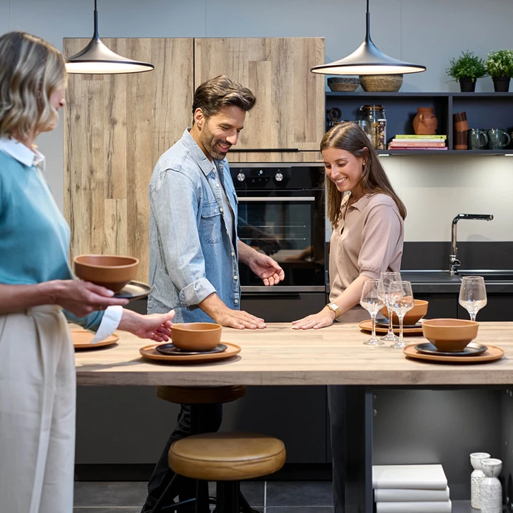 Technicien en salopette bleue installant un four encastrable dans une cuisine moderne blanche